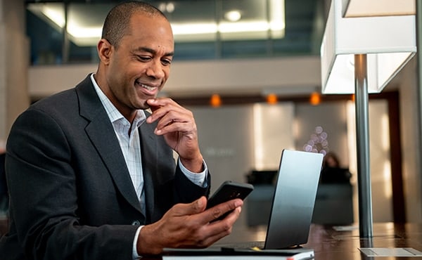 man working on laptop and phone