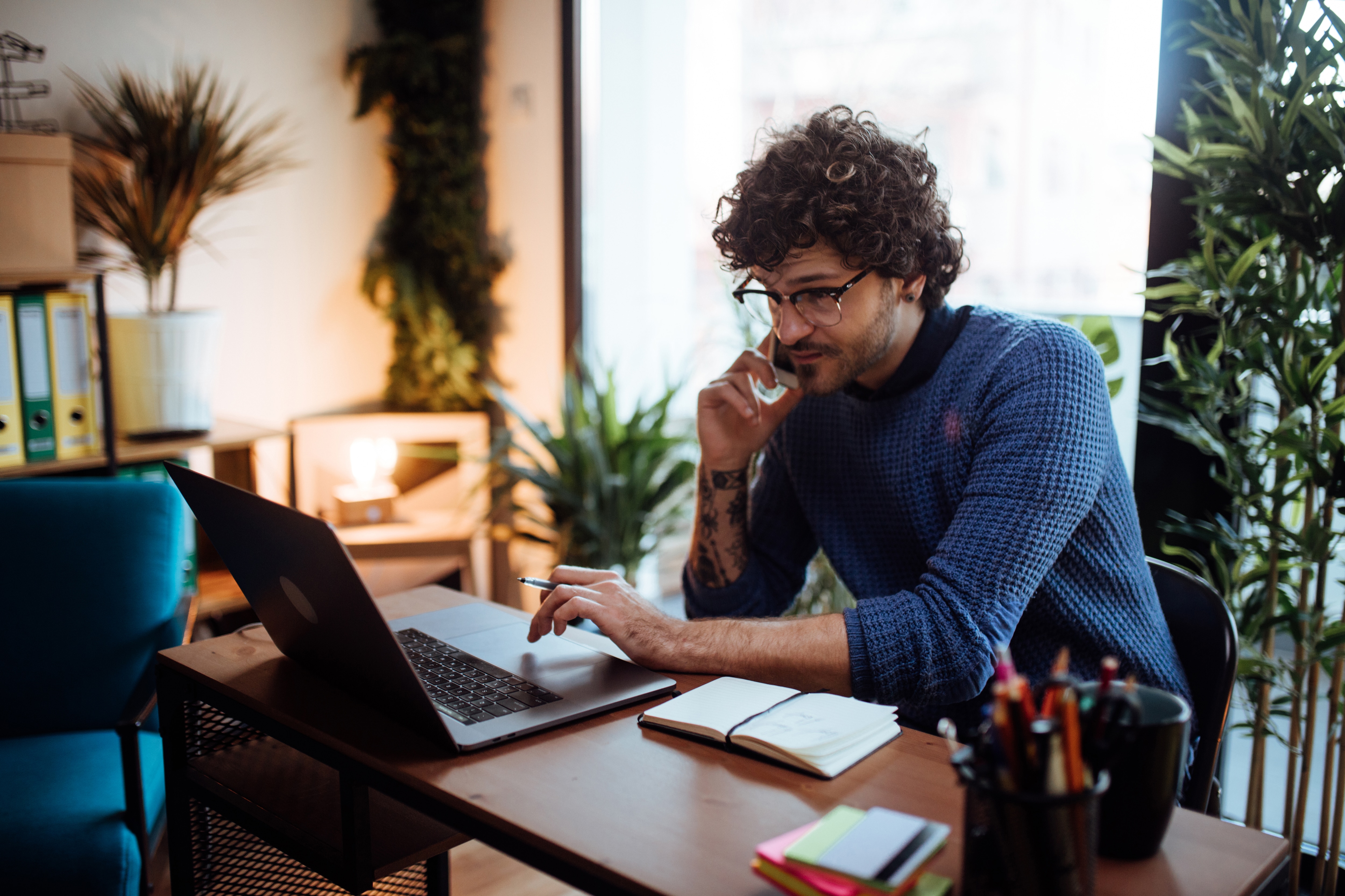 a man at the desk looking at the laptop screen 