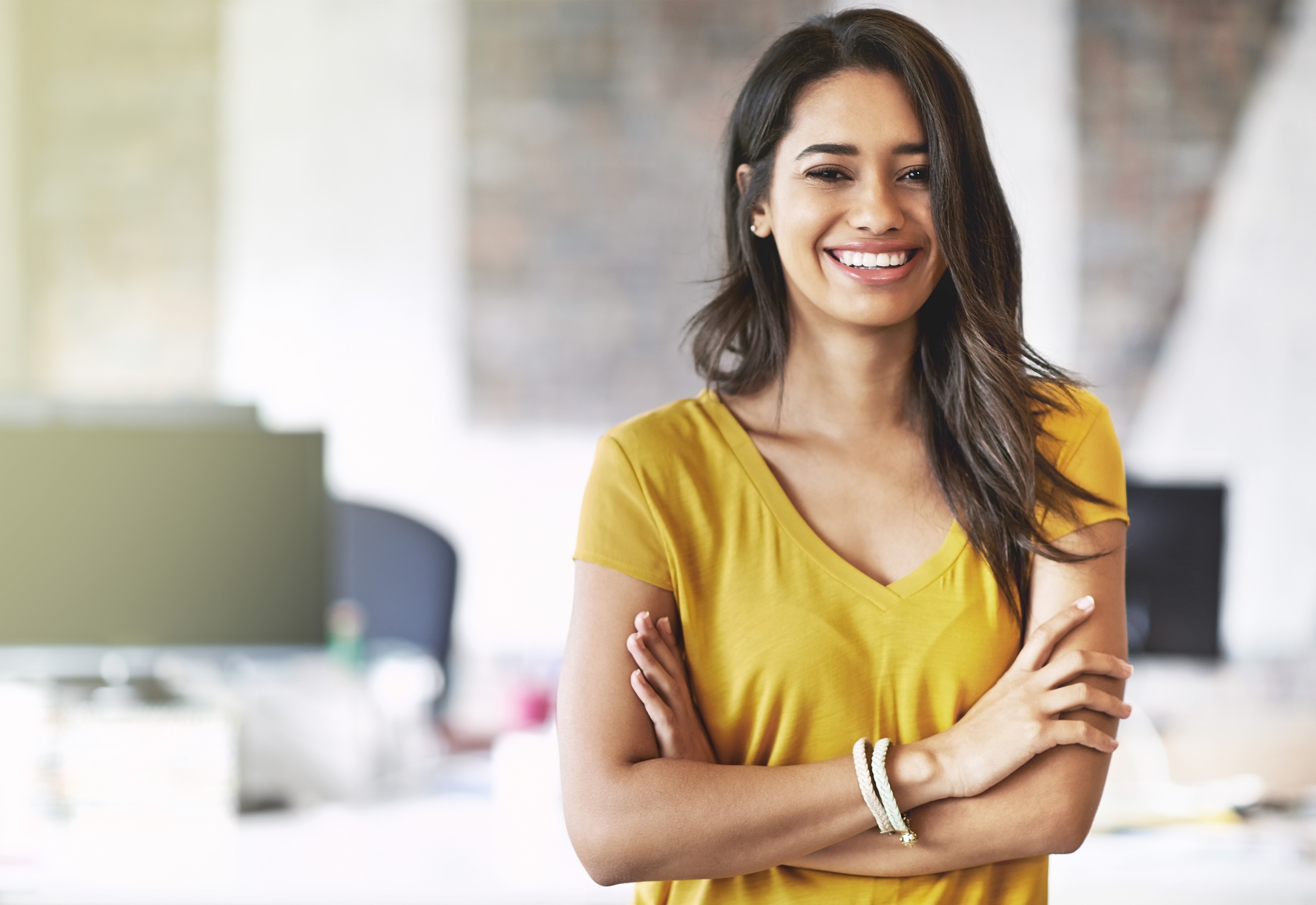 yellow shirted person standing with arms crossed and smiling