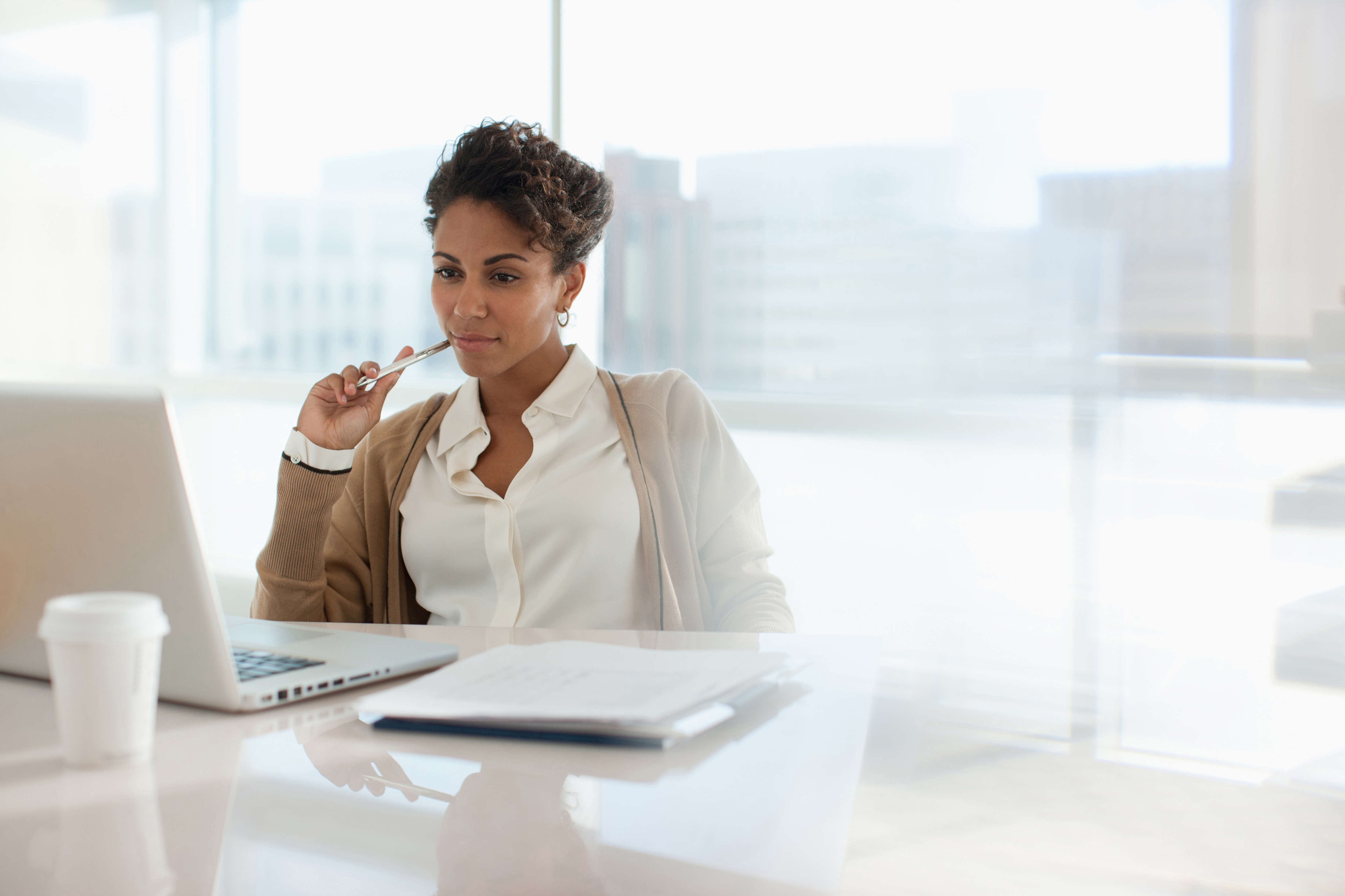 A woman sitting at a desk contemplating over her computer