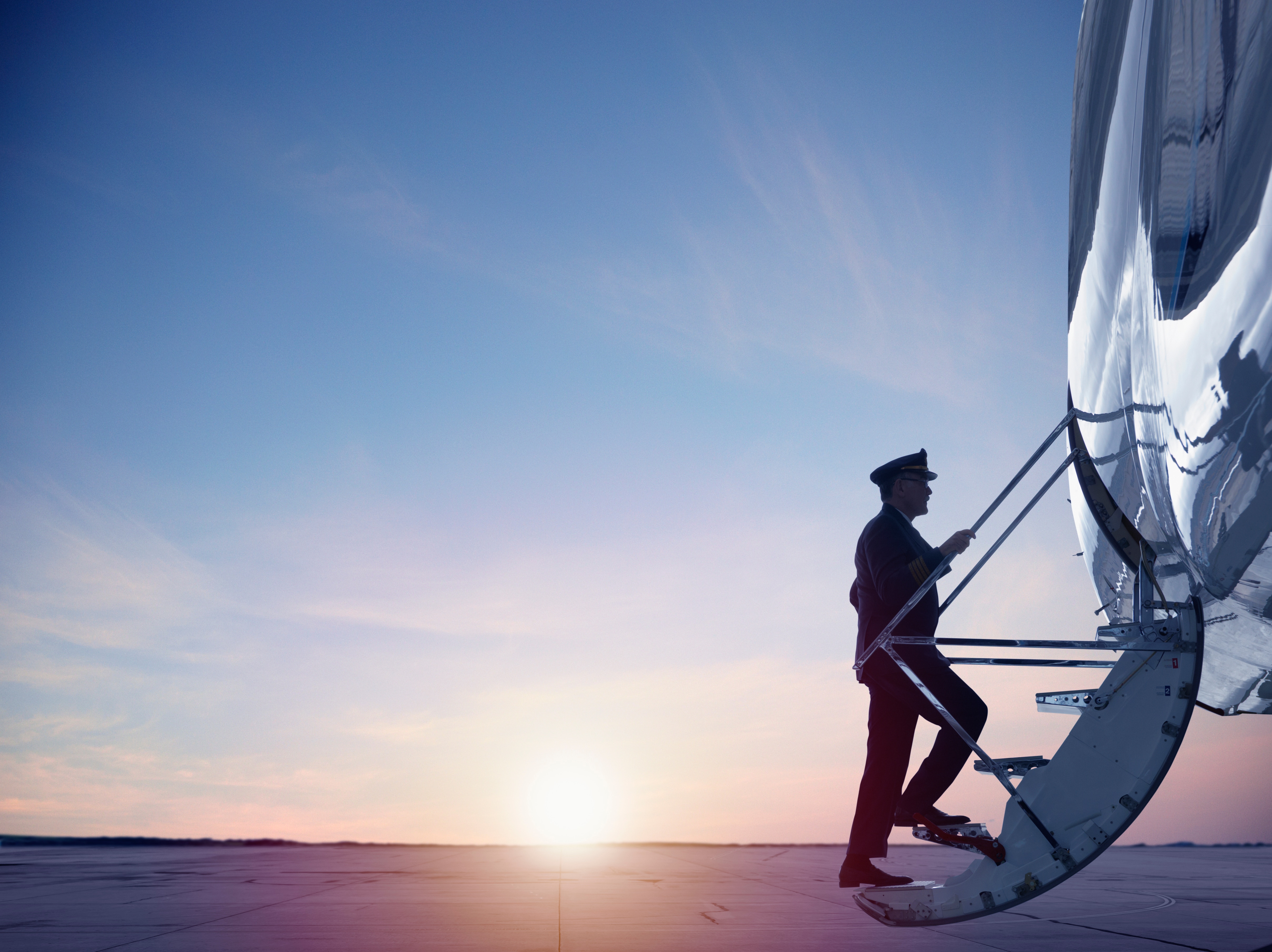 Pilot getting onto an airplane with the sunset in the background