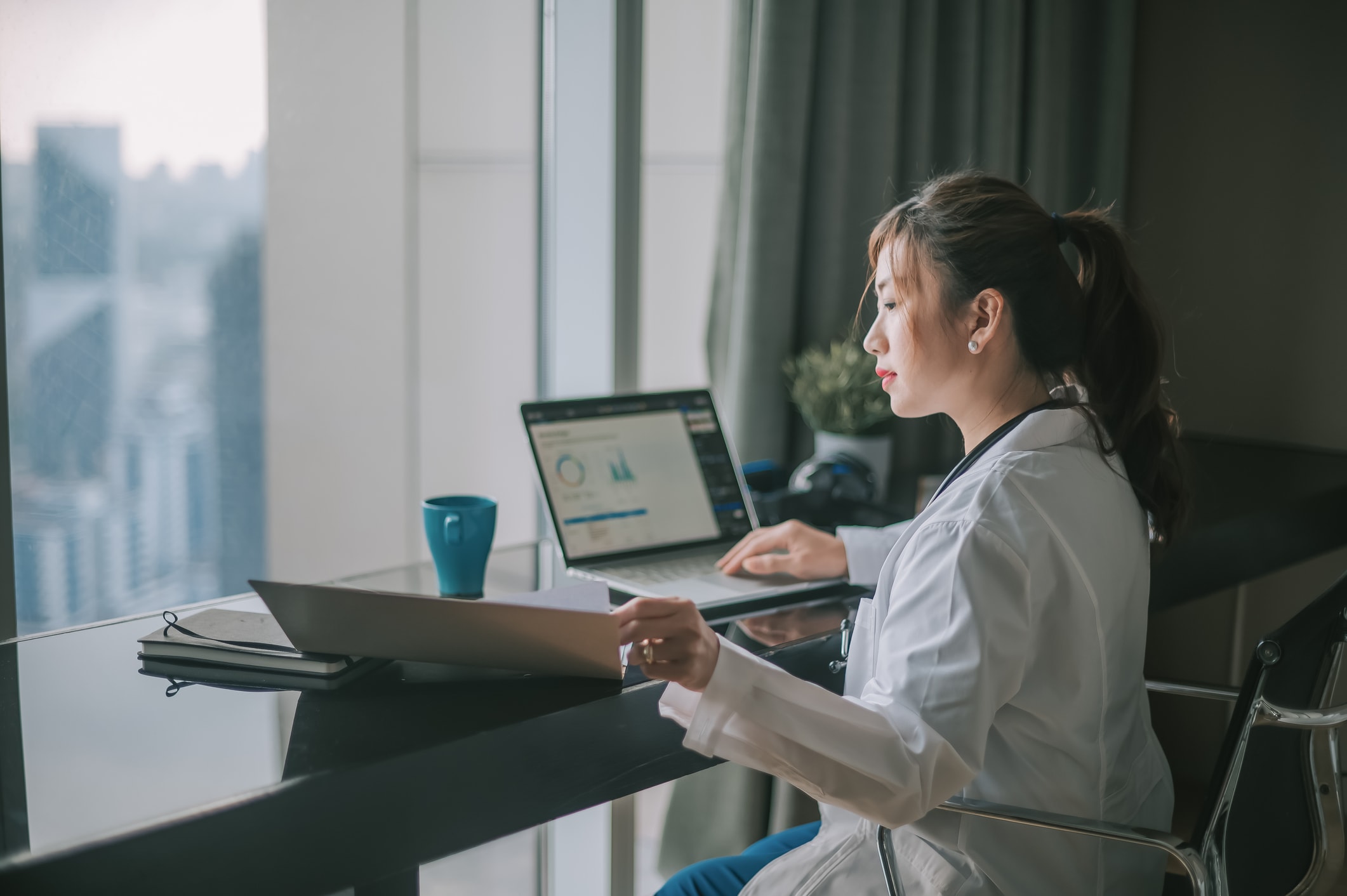 Woman doctor working at a desk looking at charts