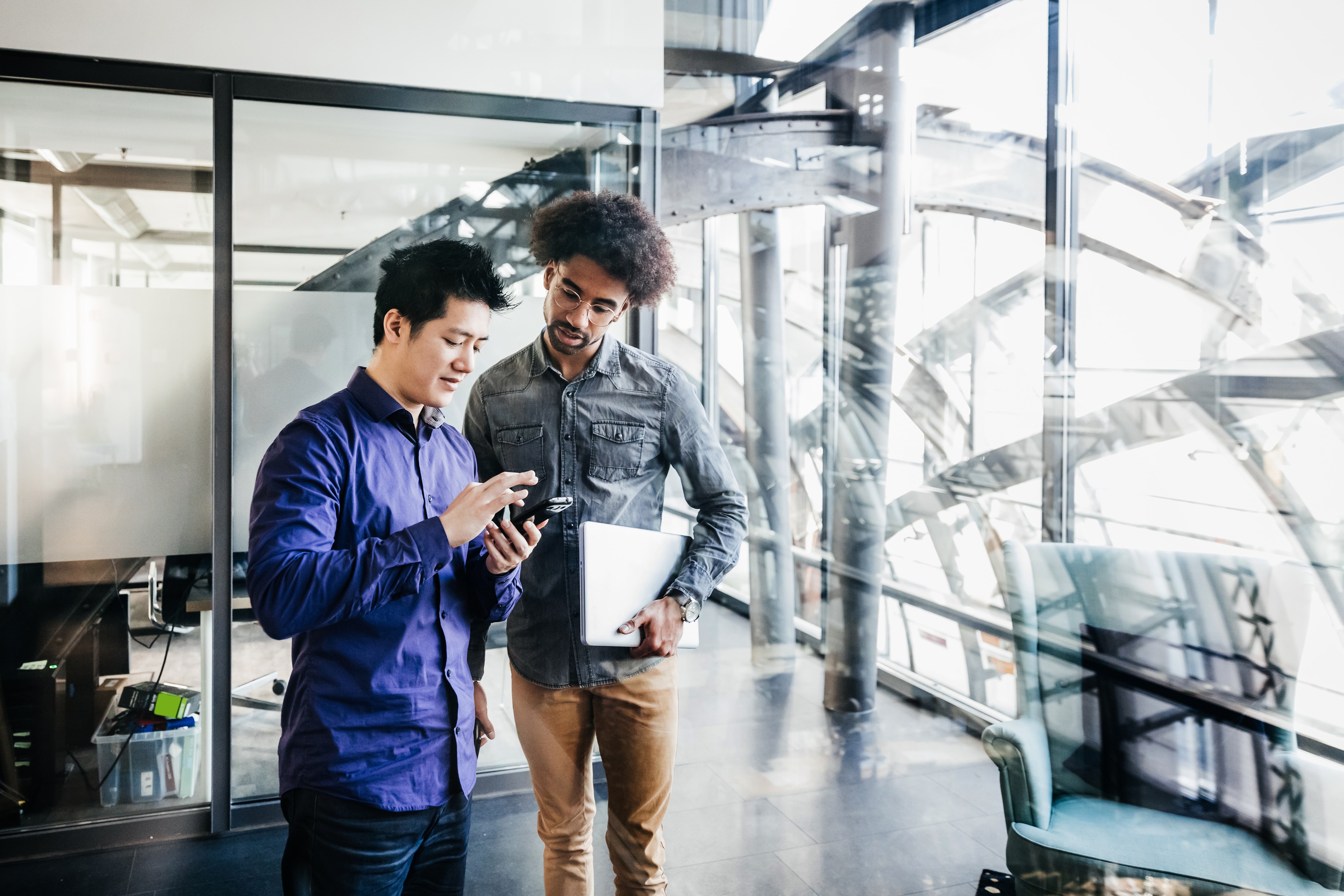 Two men looking at a phone in an office