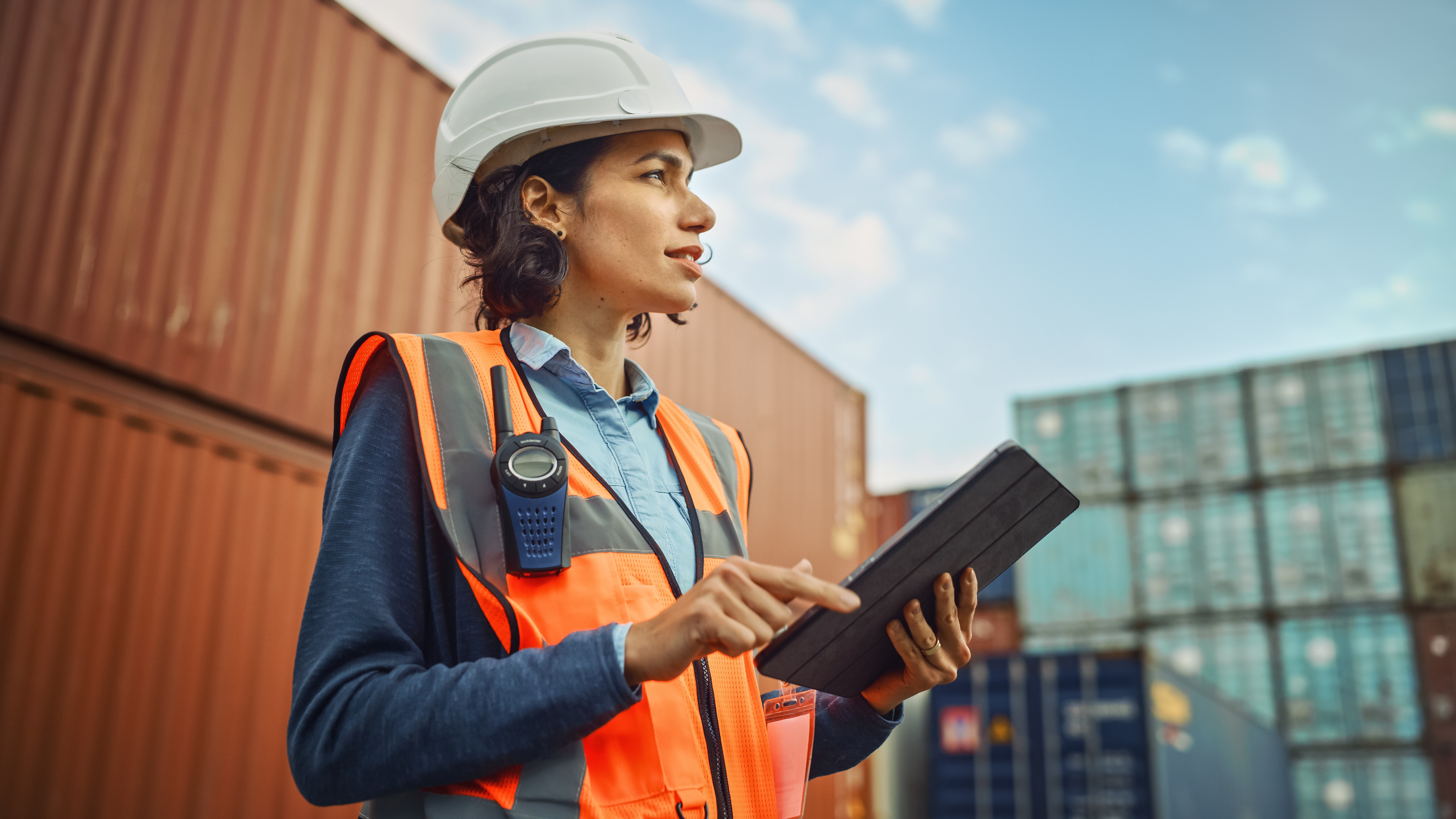 Factory worker in protective gear references a document on a clipboard