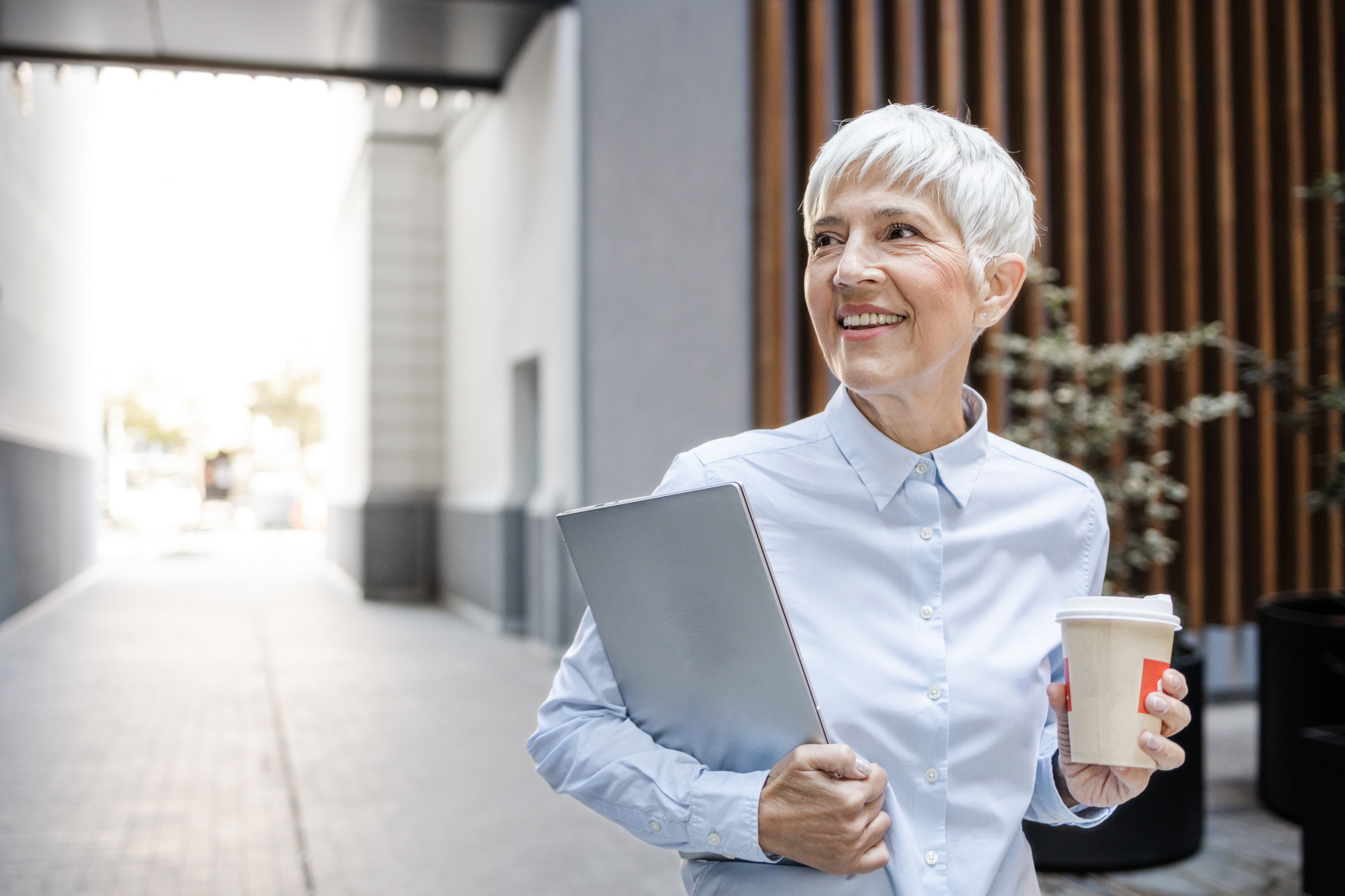 a woman holding a laptop and a cup of coffee