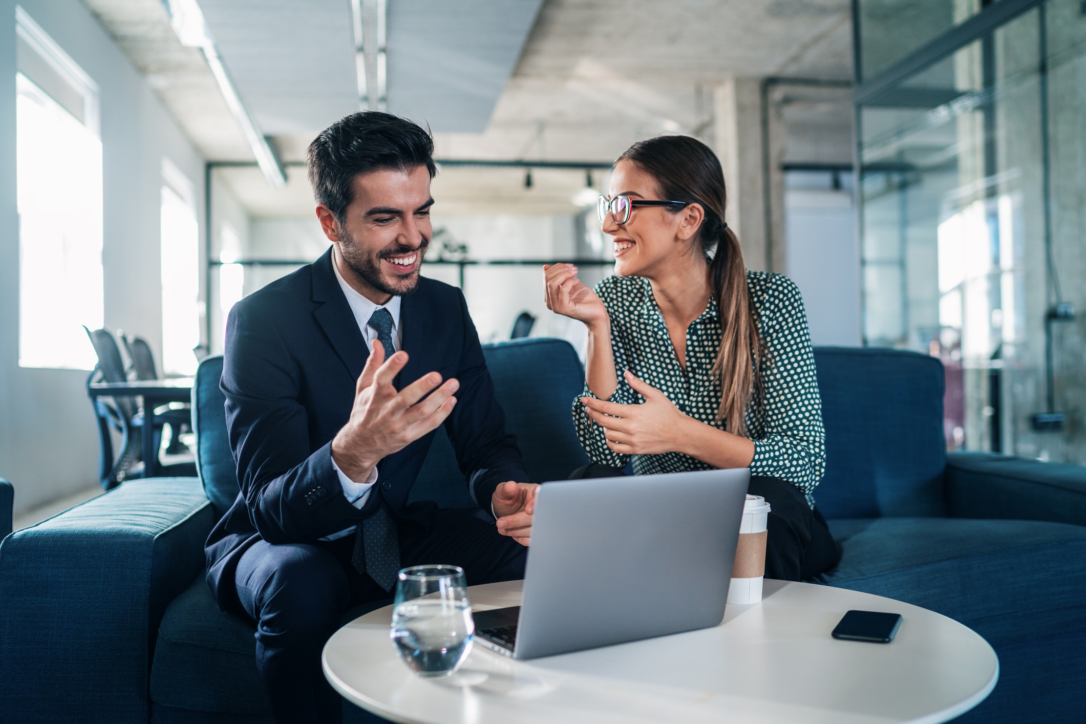 Two coworkers talking with their laptop open