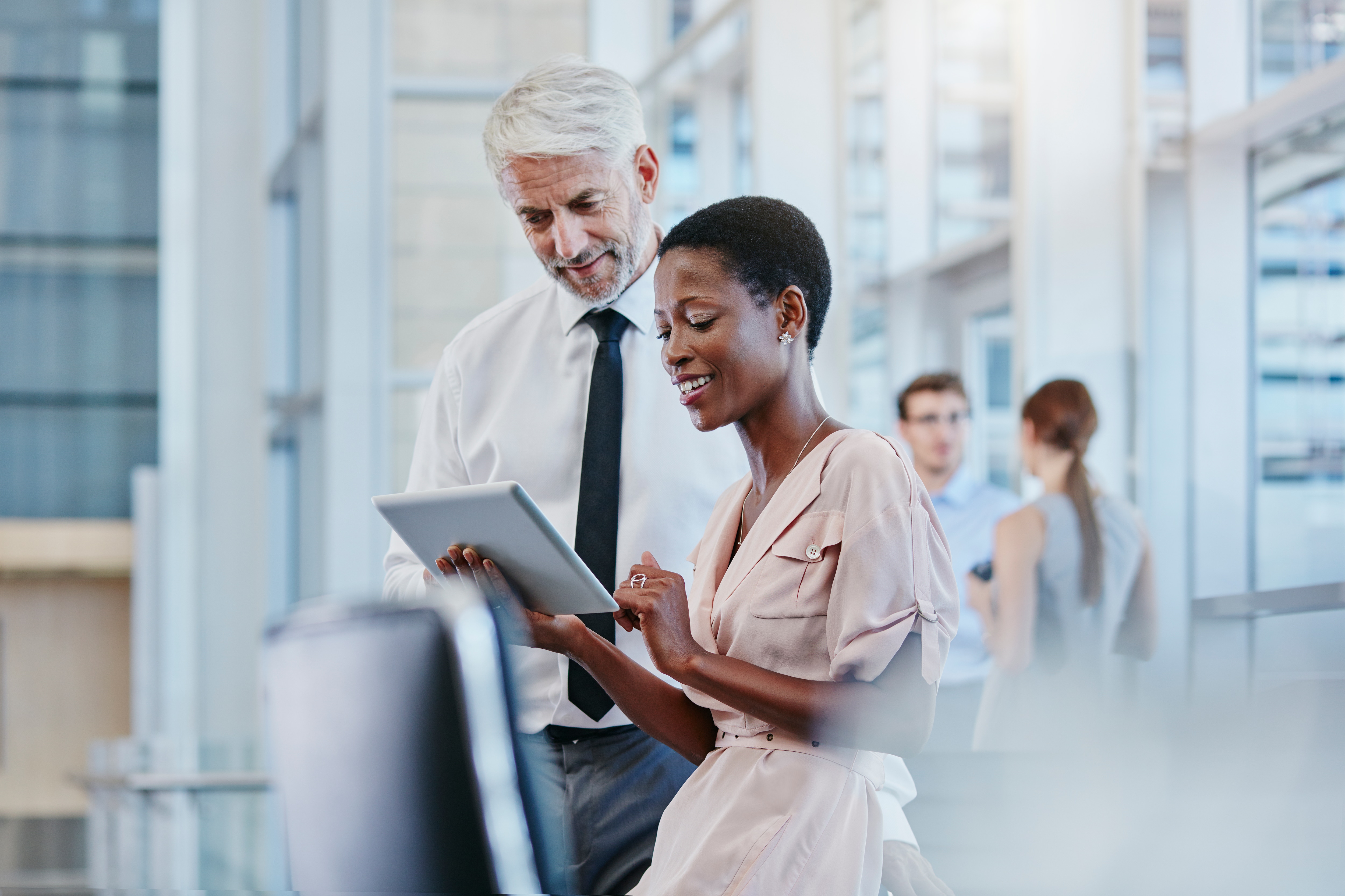 Two people in an office looking at a tablet