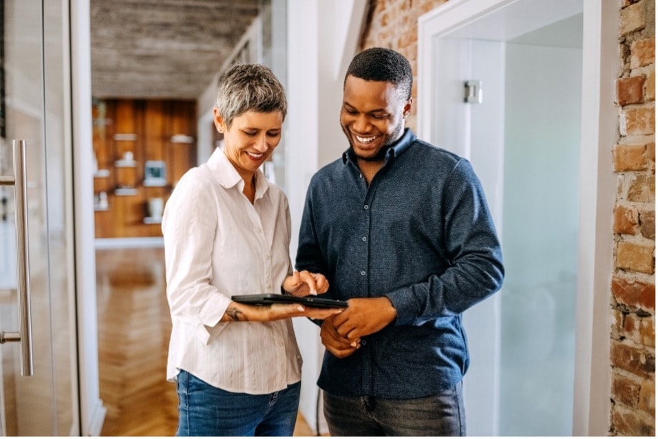 smiling woman and smiling man looking at tablet