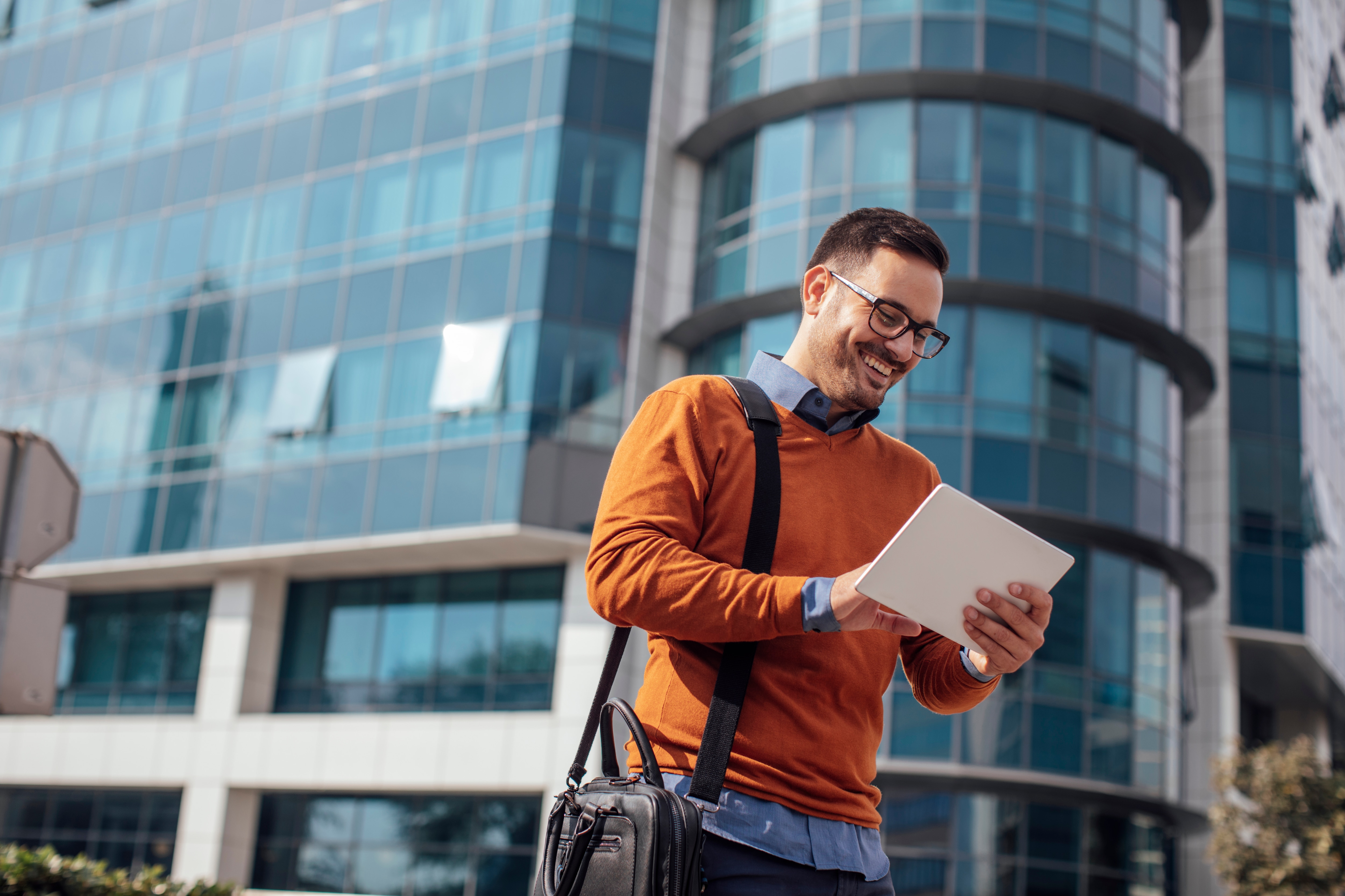 Man walking holding tablet smiling 